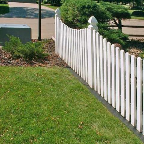 Rubber mow strip under wooden fence. Image courtesy of Bruckman Rubber Co.
